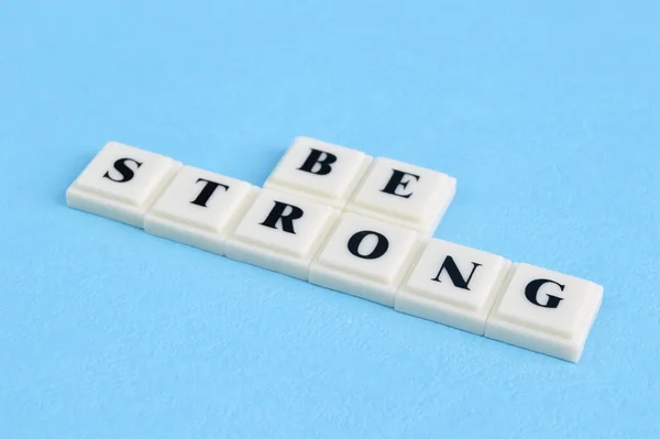 Vierkante Letters Met Tekst Strong Geïsoleerd Een Blauwe Achtergrond — Stockfoto