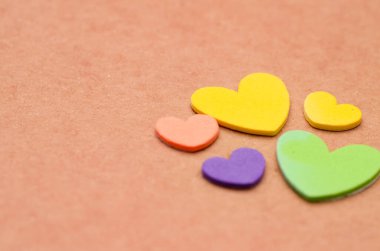 Yumuşak bir arkaplanda renkli kalp kesikleri, aşk, hayırseverlik ve birliktelik temalarını temsil ediyor..