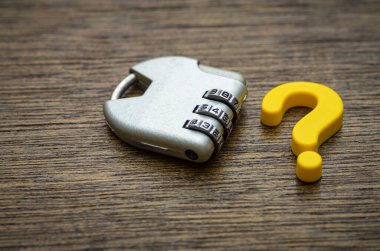 Bir asma kilit parlak sarı bir soru işaretinin yanında durur. Kilidi açmak için doğru cevabı gerektiren karmaşık bir sorunu ya da sırrı sembolize eder..