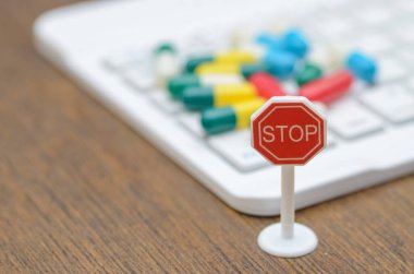 Bir klavyenin önündeki dur levhası ve haplar kontrolsüz internet uyuşturucu satışının risklerine karşı uyardı.