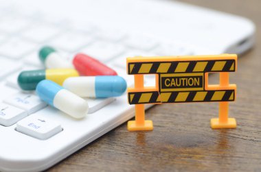 Çevrimiçi Eczanelerin Tehlikeleri. Uyarı bariyeri, klavyesi ve hapları olan güçlü bir görsel metafor, kontrolsüz internet tıbbına karşı uyarı.