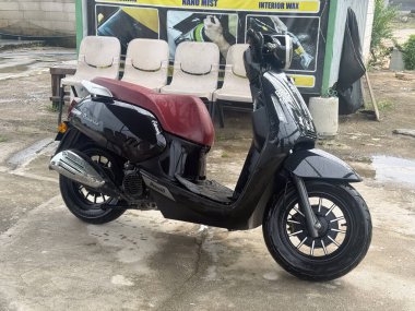 Klang, Malezya: 15 Kasım 2025 - Parlak siyah bir Benelli Panarea scooter 'ı ıslak betona park edilmiş, yeni yıkanmış gibi görünüyor.