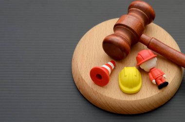 İnşaat Adaleti: Gavel, Sert Şapka ve İşçi Figürü İnşaat Kanunu ve Güvenlik Yönetmeliği Temsilcisi.