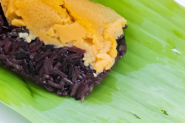 Svart klibbigt ris med vaniljsås, insvept i banan lämnar — Stockfoto