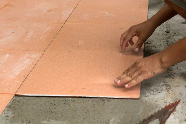 Um estucador é azulejos em casa, renovação adesiva piso de azulejos em — Fotografia de Stock