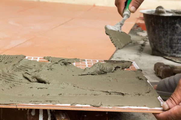 En plattsättare i arbetet. limning av golvplattor med kakel lim — Stockfoto