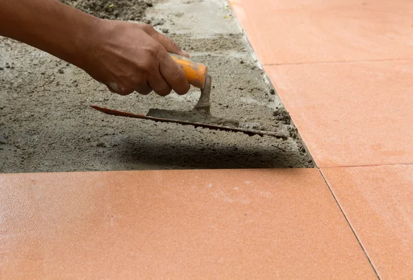 A plasterer is tiling at home, tile floor adhesive renovation Stock Image