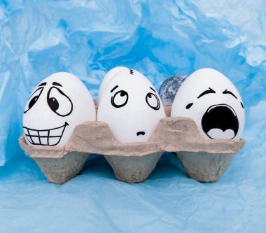 Boyalı yumurtalar. Komik duygular. Mavi arka planda yumurtalar. Paskalya yumurtaları.