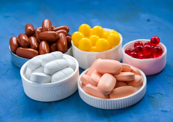 Mavi arka planda bir grup vitamin. Farklı renklerde 5 çeşit besin takviyesi