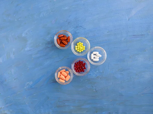 5 çeşit vitamin var. Mavi arkaplan üzerindeki renkli kapsüller