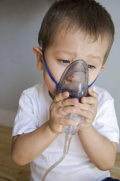 O rapaz está a inalar com um nebulizador. A criança é tratada com uma tosse. — Fotografia de Stock