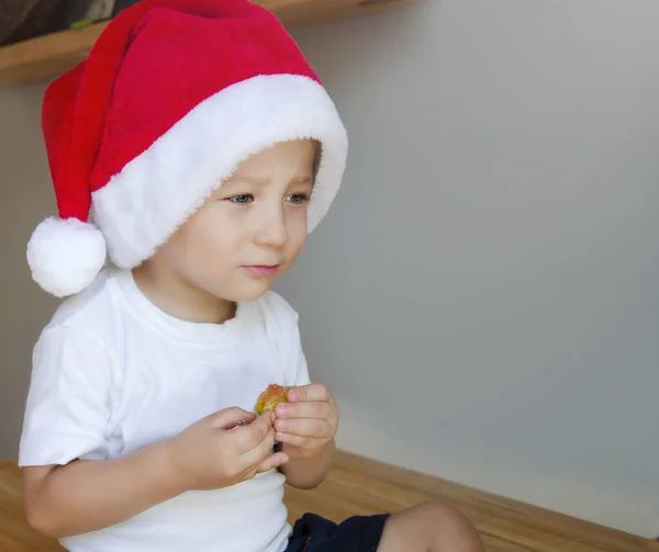 Bir çocuk Noel şapkasıyla şeker yiyor..