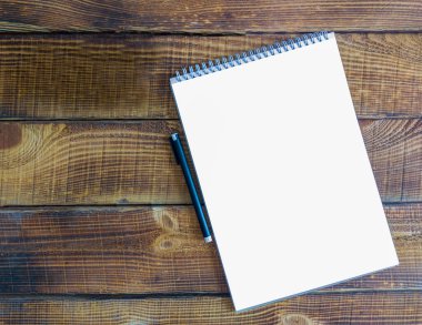 Tahta bir masanın üzerinde beyaz bir kağıt parçası.