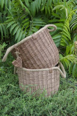 2 sepet bir ağacın altında, çimlerin üzerinde duruyor. Jüt saplı el yapımı organizatörler. Hasır sepetler evin bahçesini süslüyor..