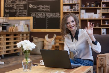 Dostça kız bir kafede bir dizüstü bilgisayar üzerinde çalışan