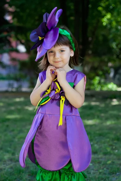 La niña con un traje de flor violeta sonríe en el bac —  Fotos de Stock