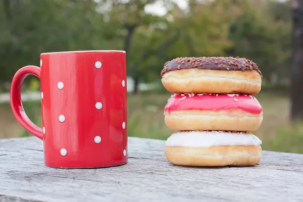 Colorful donuts with red cup of coffee