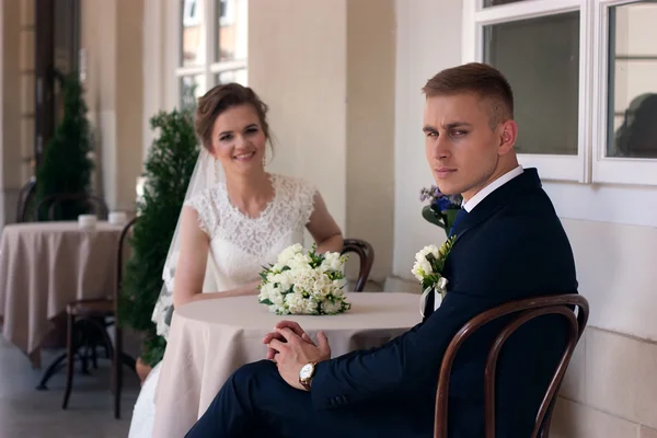 The groom looks at the camera while sitting at a table