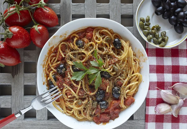 Comida italiana, pasta con tomates, aceitunas y alcaparras, llamada poner — Foto de Stock