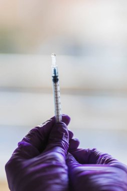 Mor eldivenli iki elle tutulan bir şırınganın ayrıntıları.