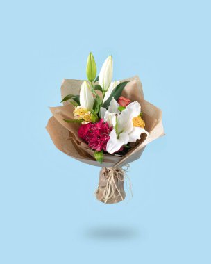 A vintage bouquet of fresh Spring flowers and lilies. Creative pastel colored concept of flowers on soft blue background.