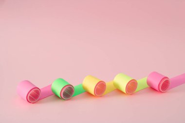 Parlak renkleri yaratıcı bir şekilde çarpıtan az miktarda saç bigudisi. Pembe arka planda bu saç modelinin kuaförüsün..