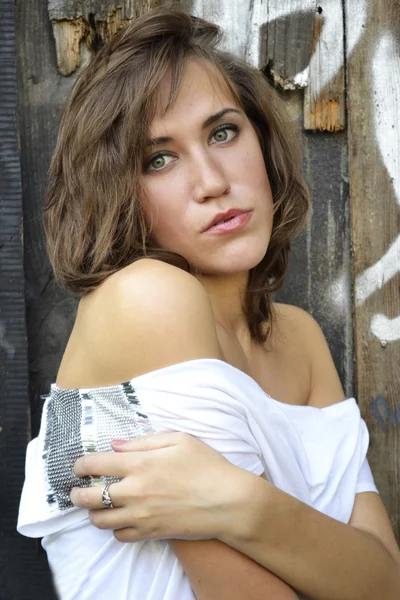 Portrait of young beautiful girl on the background of a wooden wall — Stock Photo, Image