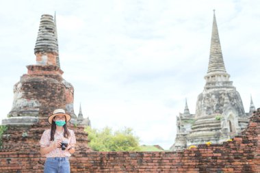 Cerrahi maske takan genç Asyalı turistler ve ellerinde eski başkent pagoda ya da eski moda bir kamera tutuyorlar. Covid-19 salgını sırasında seyahat etmek ve yeni normal kavram.