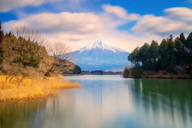 Tanuki Gölü 'ndeki Fuji Dağı' na uzun süre maruz kalınca manzara bulutlu gökyüzü ve ön planda su yüzeyi ile yansıması..