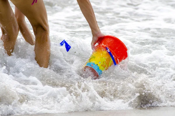 Ведро и играть для ребенка, омытого морем с руками и ногами — стоковое фото
