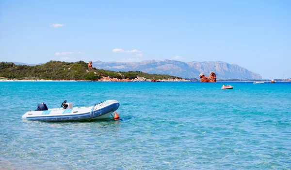 Fehér gumi csónak a tiszta, kék tenger és a hegyek a háttérben — Stock Fotó