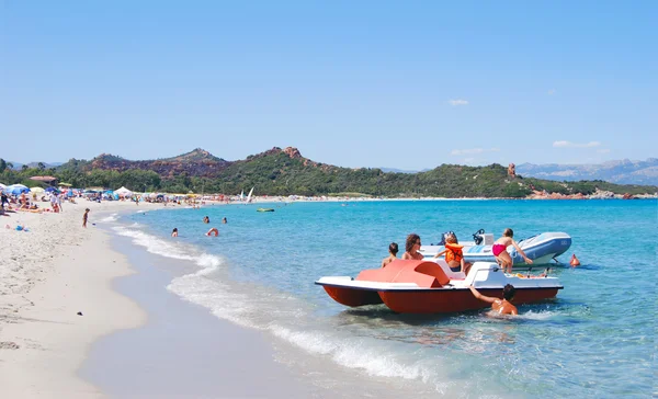 Praia de verão branco com mar azul, pessoas, barco e pedal — Fotografia de Stock