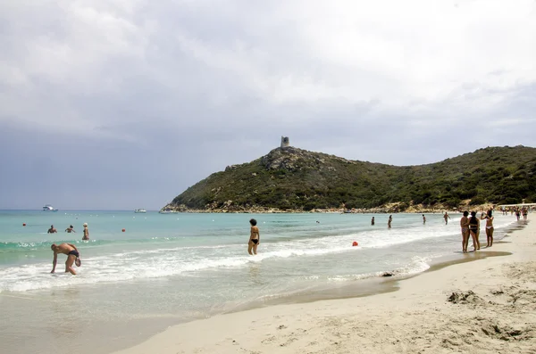 Oidentifierade personer i blå strand med några personer och grå mulen himmel — Stockfoto