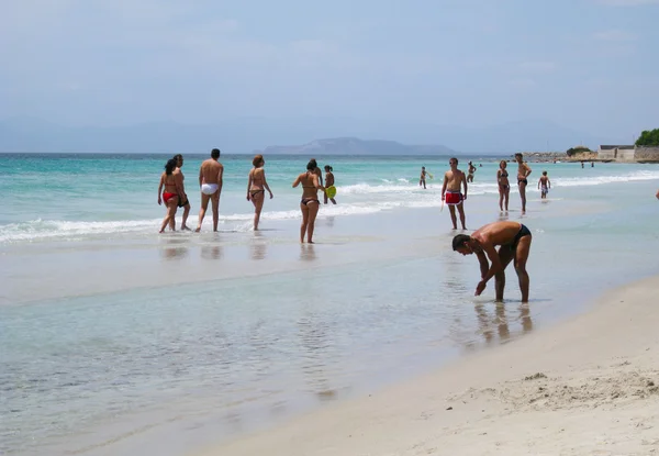 Niet-geïdentificeerde mensen in witte strand met blauwe kristalheldere zee en golven in de zomer — Stockfoto