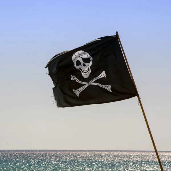 Bandeira pirata acenando com fundo azul do mar — Fotografia de Stock