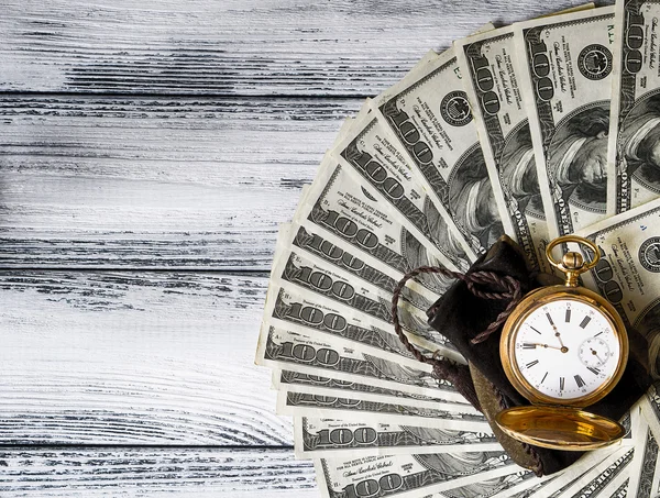 Pilha de dinheiro dólares dispostos como um ventilador com relógio de ouro antigo no fundo de madeira retro branco estilizado efeito HDR — Fotografia de Stock