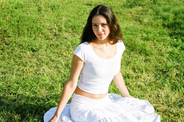 Menina morena jovem em vestido branco na grama verde — Fotografia de Stock