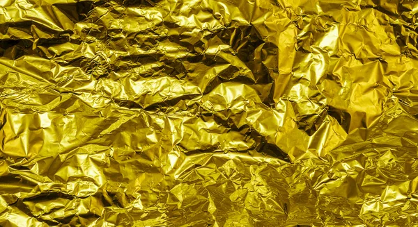 Gold crumpled aluminum foil texture background high contrasted