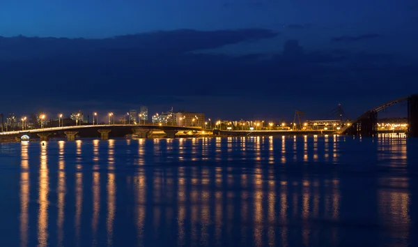 Luci notturne città e ponte con riflessi sul fiume — Foto Stock