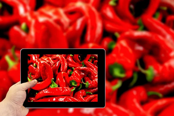 Tablet photography concept. Taking pictures on a tablet. Red chili pepper high contrast background