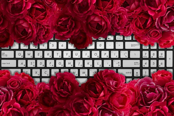 Clavier moderne pour ordinateur portable noir et chromé avec buisson de fleurs roses rouges — Photo