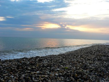 Bulutlu gökyüzü, ışınları ışık ve plajı ile deniz on Sunset