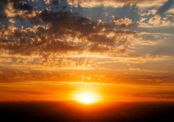 Céu nublado azul bonito com pôr do sol vermelho dourado e raios de luz — Fotografia de Stock