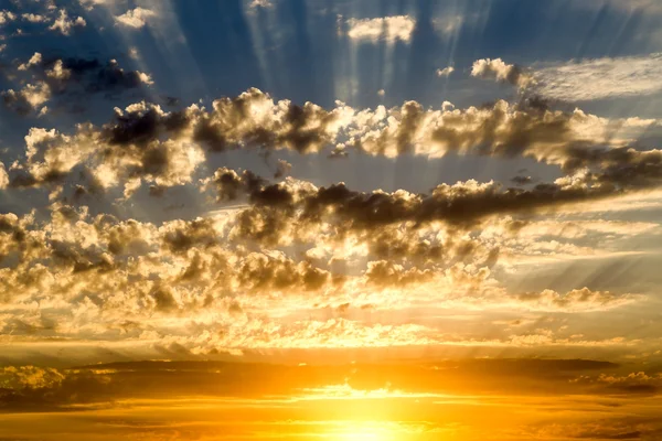 Hermoso cielo nublado azul con puesta de sol de color amarillo dorado y rayos de luz — Foto de Stock