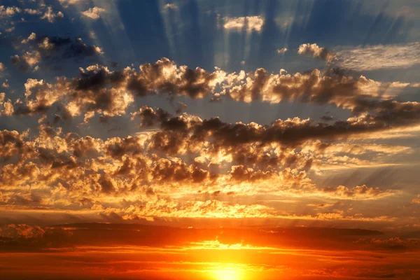 Прекрасне блакитне хмарне небо з золотистим червоним заходом сонця і променями світла — стокове фото