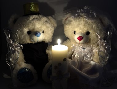 Wedding setting: hand made teddy boy and girl, white and gold candle, wedding glasses by candlelight