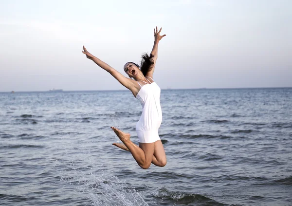 Felice ragazza bruna saltando sul mare — Foto Stock