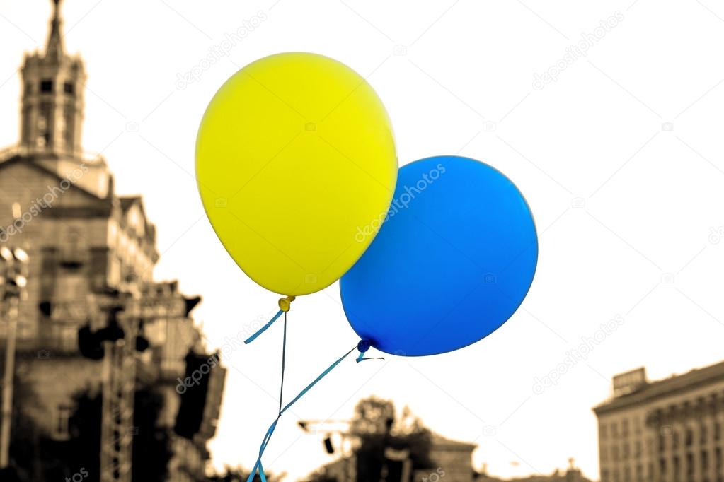Flying balloons with colors of flag of Ukraine in city center styled