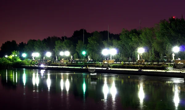 Luces del centro comercial nocturno de la ciudad con reflejos sobre el río — Foto de Stock