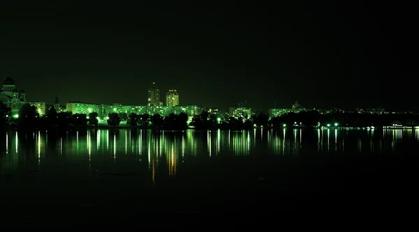 Вогні нічного міста з роздумами на річці зеленого стилю — стокове фото